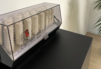 Carmen Curlers i opbevaringsboks på sort bord.